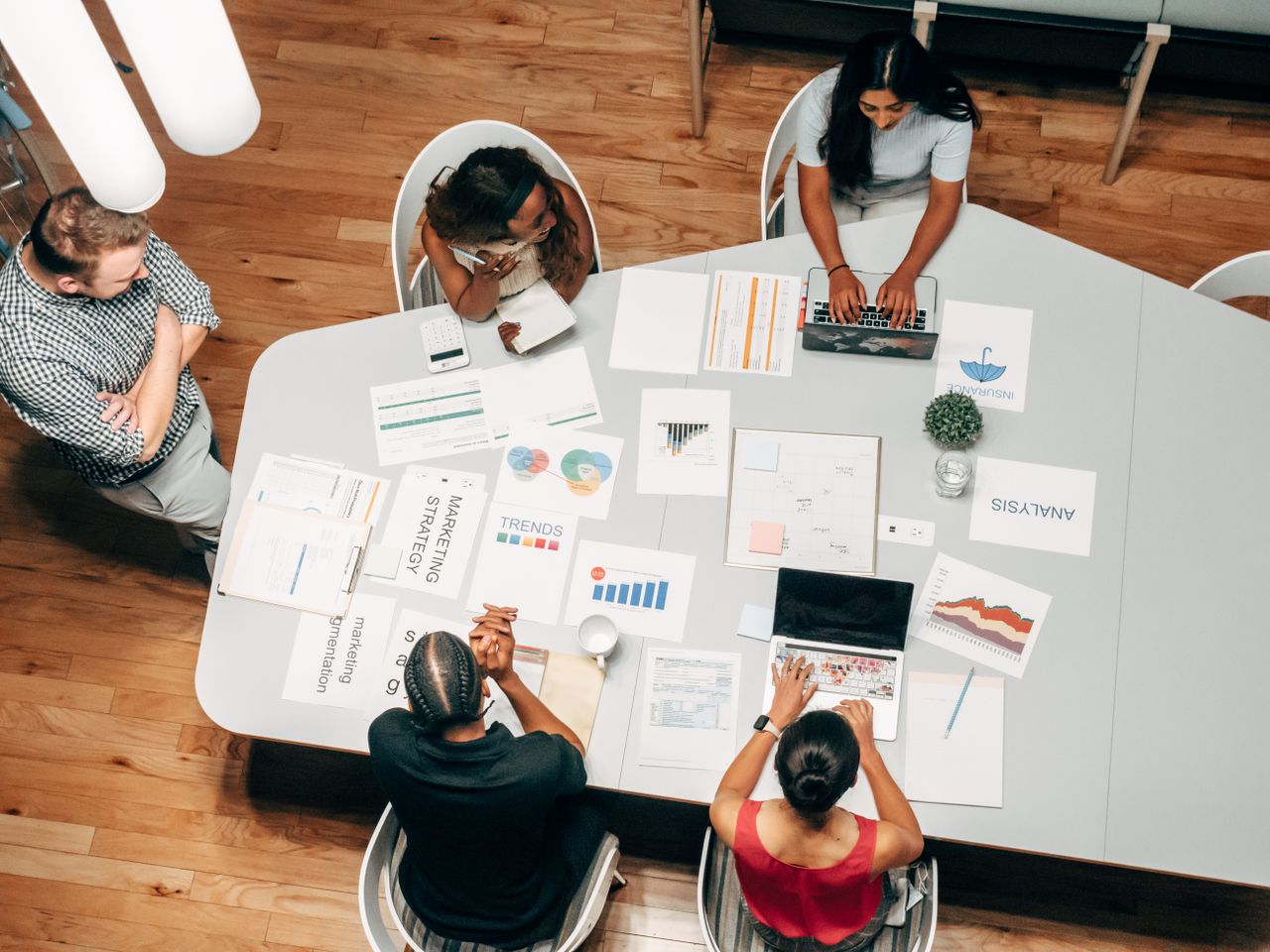 Un equipo diverso trabajando en estrategias de marketing con gráficos y portátiles en un entorno de oficina.